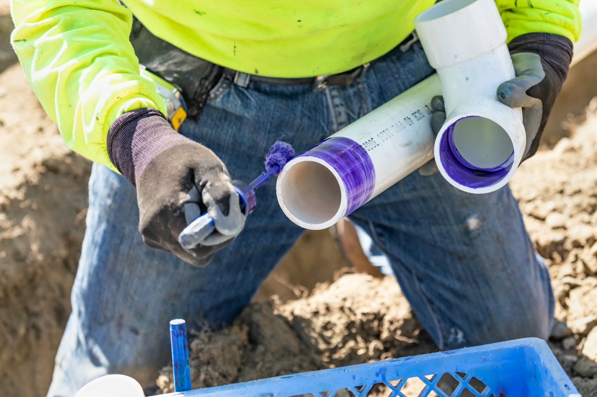 Plumber Applying Pipe Cleaner, Primer and Glue to PVC Pipe At Construction Site