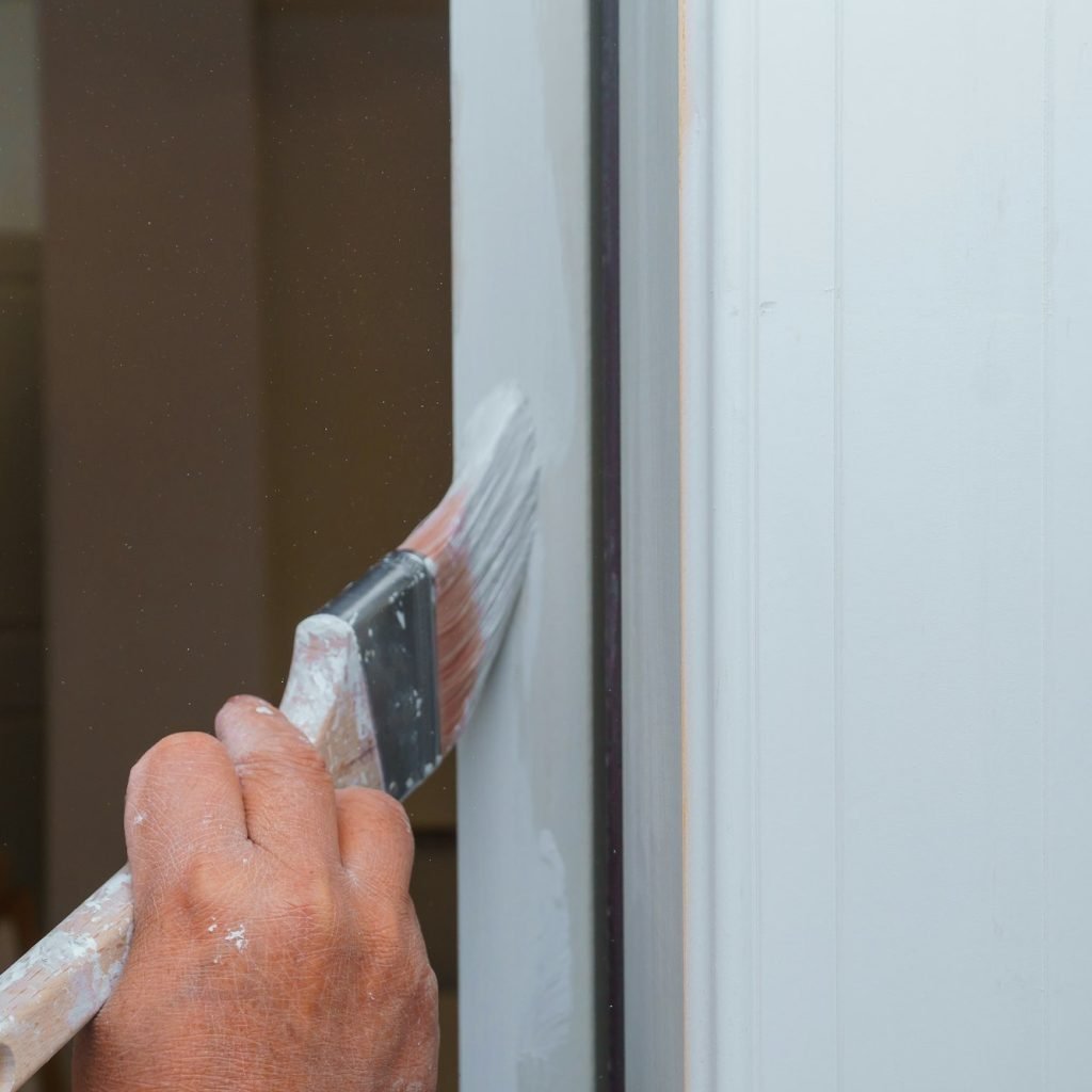 A new house painter painting the door white in door frame