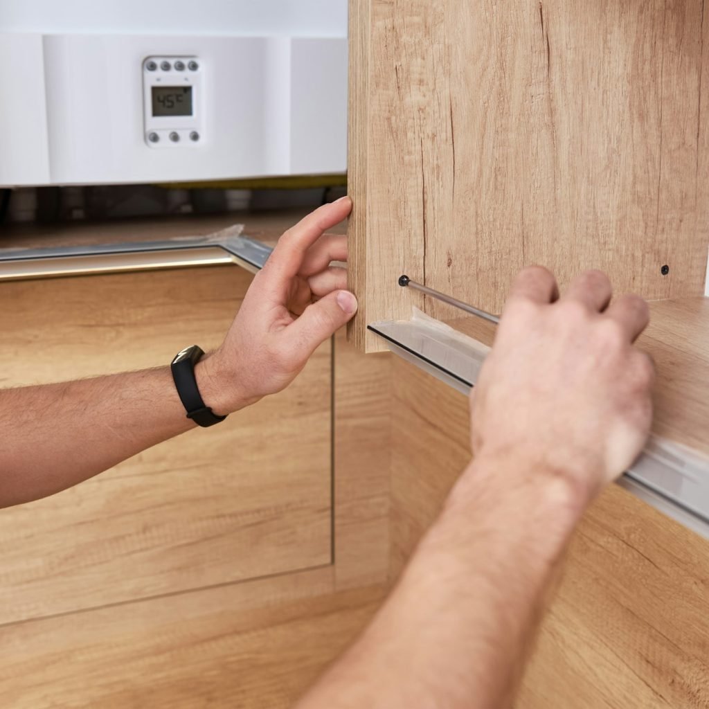 Male carpenter install shelf in kitchen cabinet