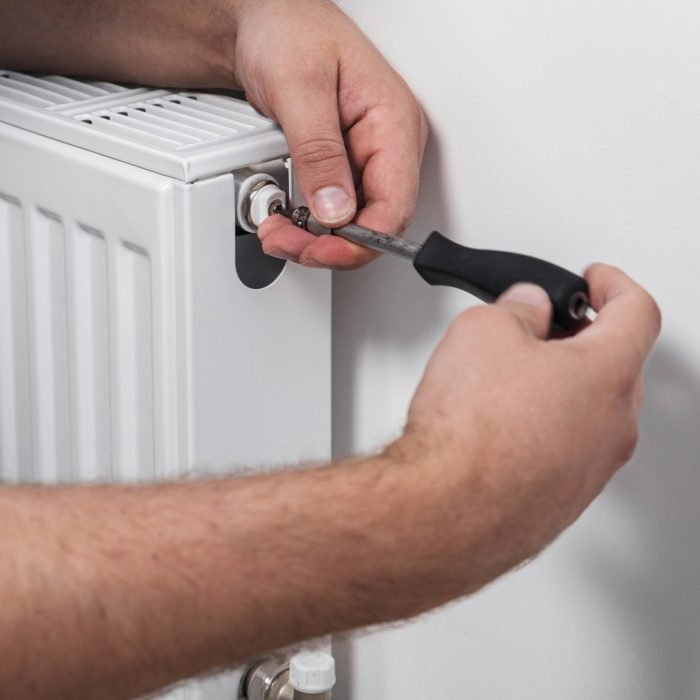 Plumber installing new steel hot water central heating radiator