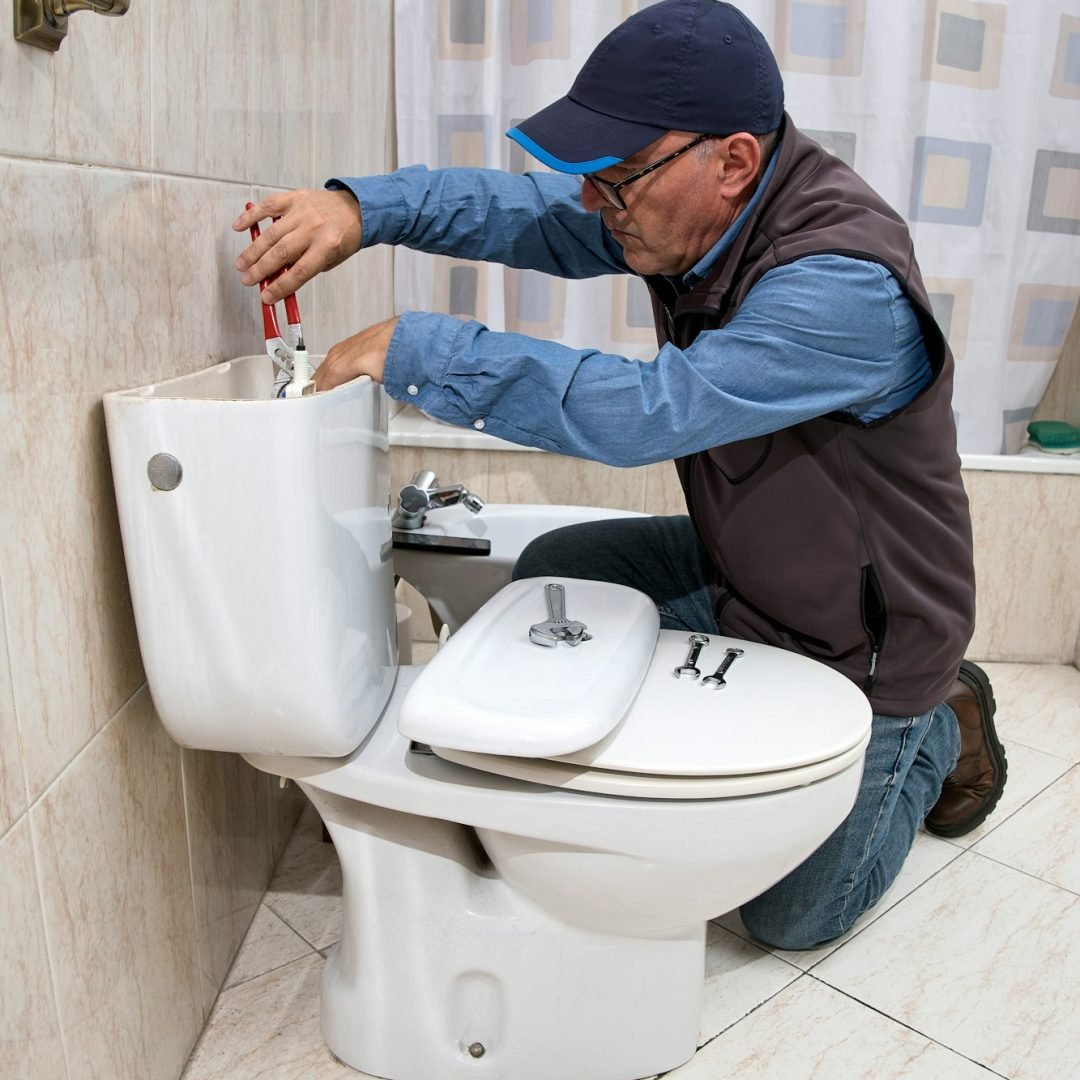 Plumber repairing a toilet cistern