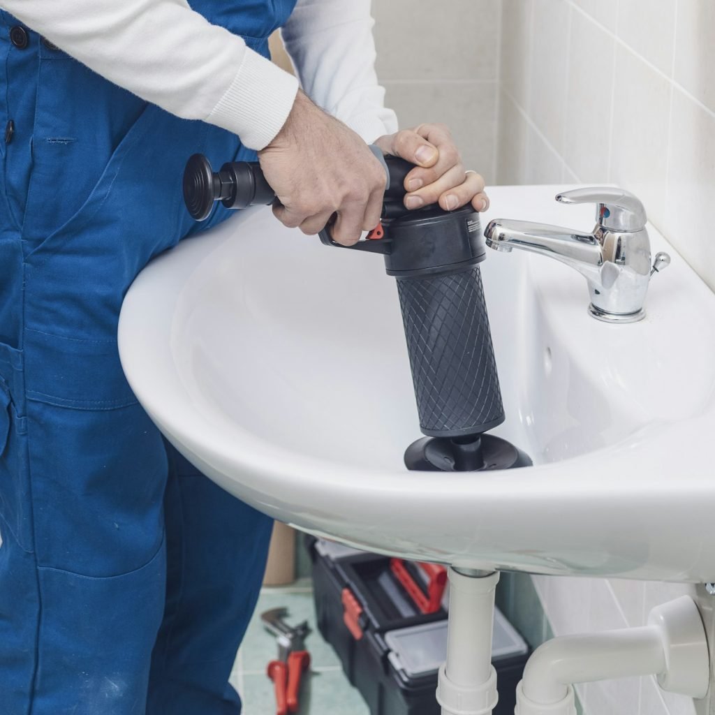 Professional plumber unclogging a sink