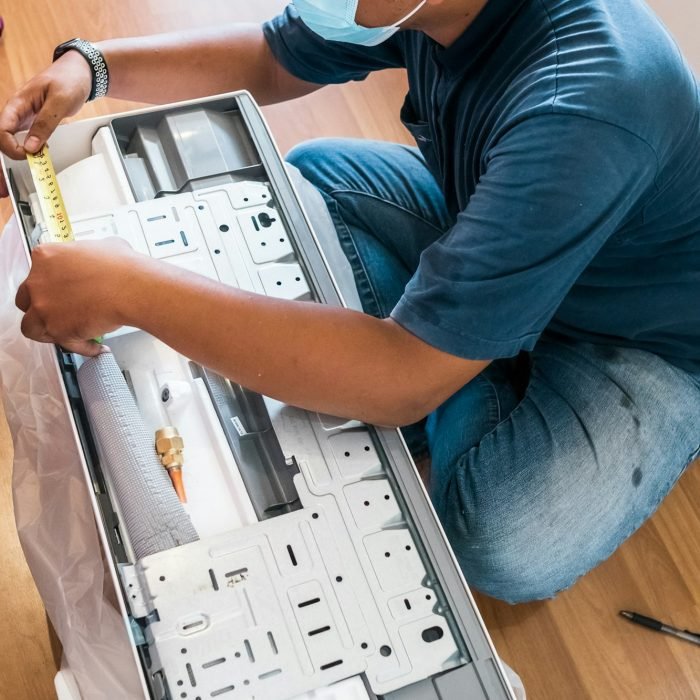 Technician assembling air conditioner on the floor.