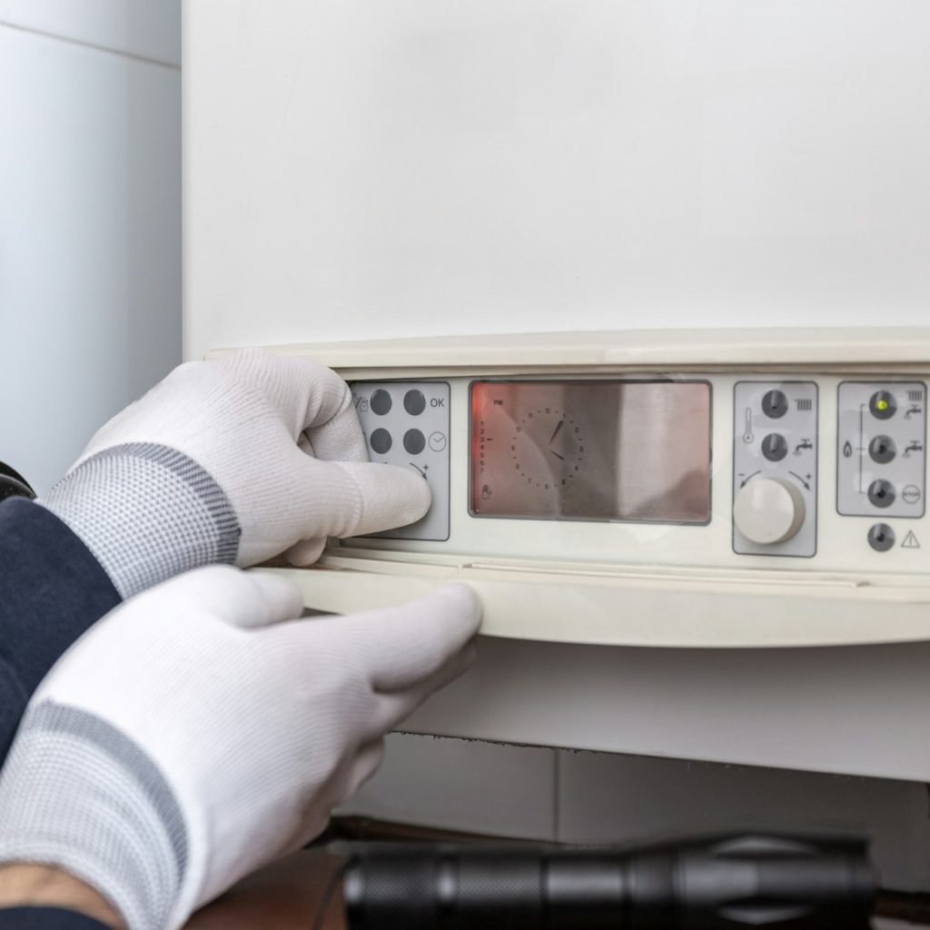 Technician servicing heating boiler in a house